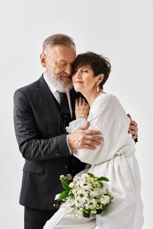 Ein Mann mittleren Alters im Anzug umarmt liebevoll eine Frau im weißen Kleid, die ihren besonderen Tag im Studio feiert.