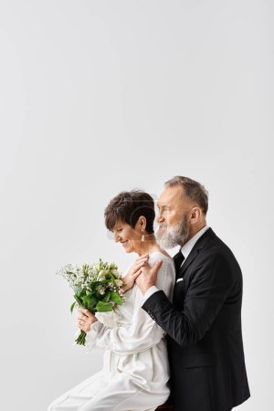 A middle aged bride and groom in wedding gowns celebrating their special day in a studio setting.