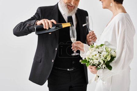 Braut und Bräutigam mittleren Alters halten in Hochzeitskleidung freudig Champagner in einem Studio-Ambiente.