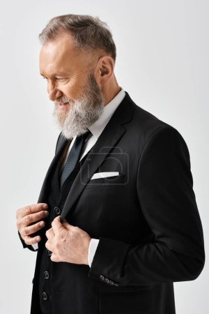 A middle-aged groom is elegantly adjusting his tie in a studio setting on his wedding day.
