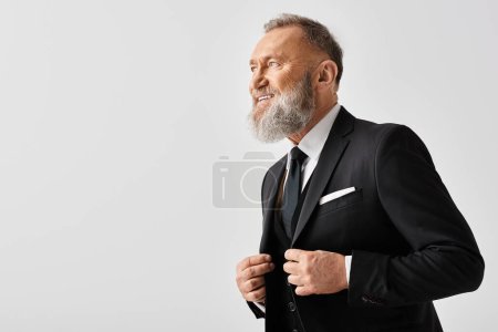 Ein Bräutigam mittleren Alters in elegantem Anzug und Krawatte, der am Hochzeitstag einen gepflegten Bart zur Schau stellt.
