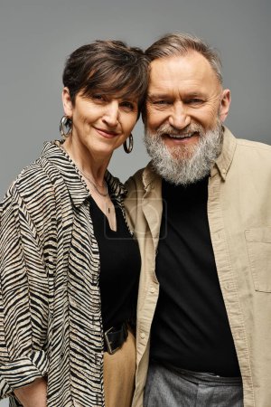Foto de Un hombre y una mujer de mediana edad vestidos con un atuendo elegante de pie uno al lado del otro en un entorno de estudio. - Imagen libre de derechos