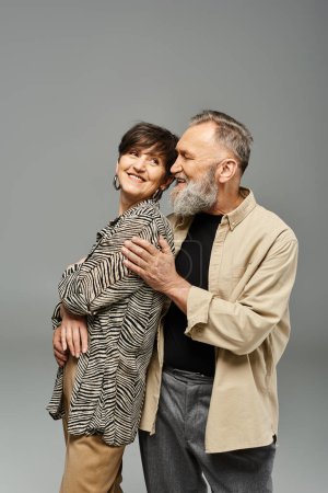 A middle-aged couple dressed in stylish attire sharing a warm and affectionate hug in a studio setting.