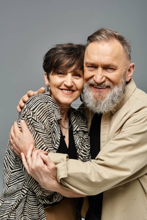 Middle-aged couple in stylish attire lovingly embrace each other in a studio setting.