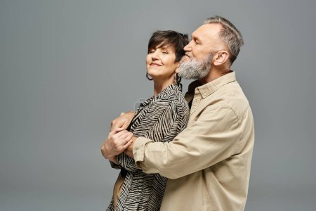 A middle-aged couple in stylish attire embracing each other warmly in a studio setting.