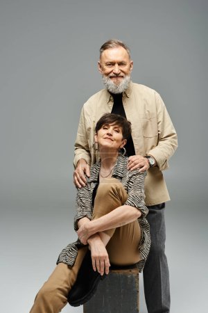Ein Paar mittleren Alters in stilvoller Kleidung posiert für ein Porträt in einem Studio-Setting.