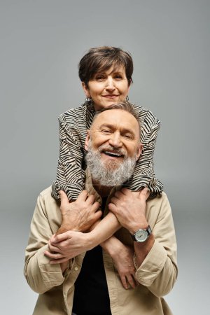 A middle-aged man holding a woman on his shoulders in a stylish studio setting.