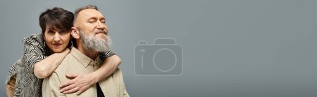 Téléchargez les photos : Un homme et une femme d'âge moyen en tenue élégante partagent une étreinte sincère dans un cadre de studio. - en image libre de droit
