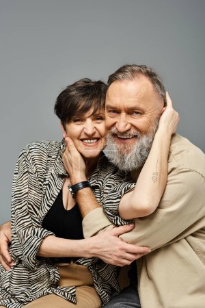 A middle-aged couple in stylish attire hugging each other tightly, showing love and closeness in a studio setting.