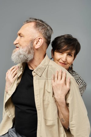 Ein Mann mittleren Alters und eine Frau in stilvoller Kleidung posieren in einem Studio für ein modisches Porträt.