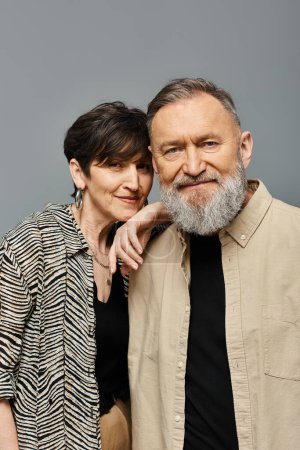 Ein Mann mittleren Alters und eine Frau in stilvoller Kleidung posieren anmutig für ein Porträt in einem Studio-Setting.