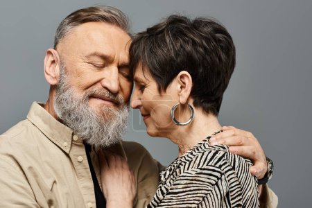Téléchargez les photos : Un homme et une femme d'âge moyen vêtus de vêtements élégants s'embrassent tendrement dans un cadre de studio, montrant amour et connexion. - en image libre de droit
