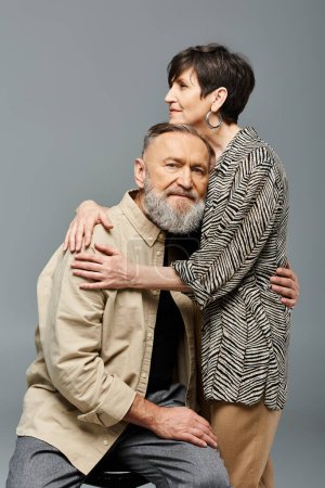 Foto de Un hombre y una mujer de mediana edad, vestidos con un atuendo elegante, comparten un abrazo tierno en un entorno de estudio, mostrando amor y conexión. - Imagen libre de derechos