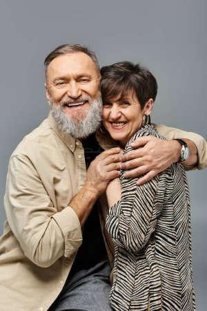 Téléchargez les photos : Un homme d'âge moyen et une femme en tenue élégante partagent un câlin sincère dans un cadre de studio, rayonnant d'amour et de connexion. - en image libre de droit