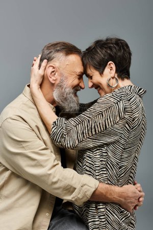 Photo for A middle-aged couple in stylish attire sharing a warm, intimate hug in a studio setting. - Royalty Free Image