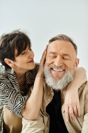 Un homme d'âge moyen et une femme en tenue élégante s'assoient étroitement ensemble, respirant un sentiment de connexion et de compagnie.