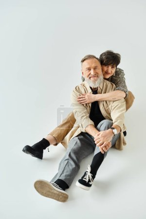 Photo for A middle-aged couple in stylish attire sits intertwined on top of each other, showcasing unity and harmony. - Royalty Free Image