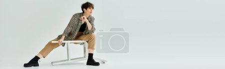 Photo for A middle-aged woman with short hair sitting on a chair, crossing her legs in a stylish and elegant manner in a studio setting. - Royalty Free Image