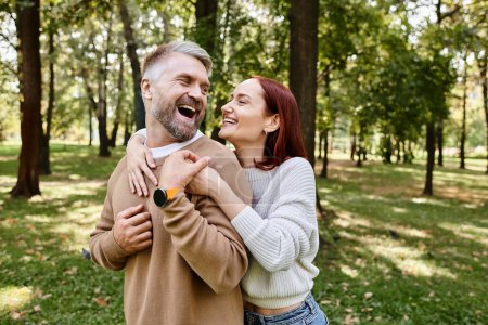 Photo for A man tenderly holds a woman in a park setting. - Royalty Free Image