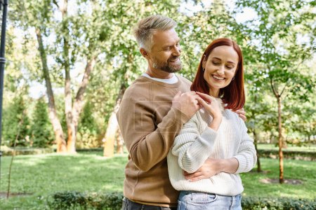 Téléchargez les photos : Un couple aimant en tenue décontractée se tient ensemble dans un parc. - en image libre de droit