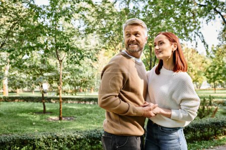 Téléchargez les photos : Un couple en tenue décontractée se tient ensemble dans un parc, profitant d'une promenade tranquille. - en image libre de droit