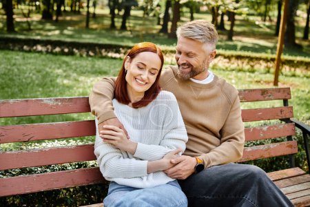 Téléchargez les photos : Un homme et une femme profitent d'un moment paisible sur un banc de parc. - en image libre de droit