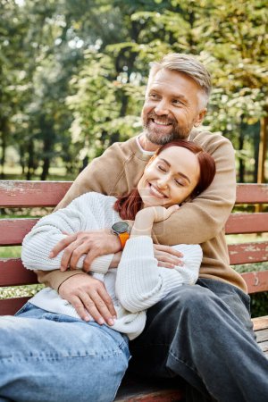Téléchargez les photos : Un homme et une femme en tenue décontractée s'assoient sur un banc de parc, profitant d'un moment paisible ensemble. - en image libre de droit