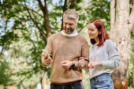 Photo for An adult man and woman in casual attire stand side by side in a park. - Royalty Free Image