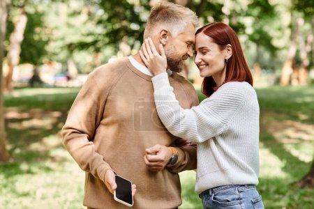 Téléchargez les photos : Un couple aimant les adultes en tenue décontractée se promène tranquillement dans le parc. - en image libre de droit
