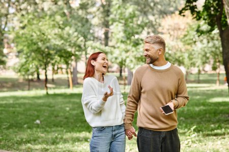 Photo for An adult loving couple in casual attires taking a walk through a serene park. - Royalty Free Image