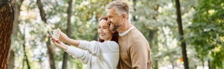 Photo for A man and woman taking a selfie in the tranquil woods during a leisurely walk. - Royalty Free Image