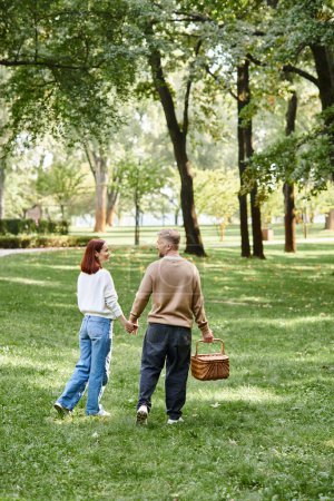 Couple strolling, holding hands in park.