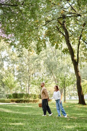A loving adult couple walks peacefully through a park.