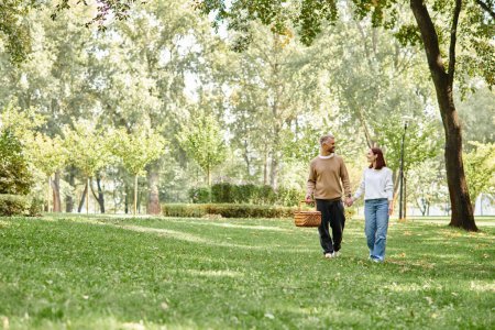 A loving couple in casual attire leisurely walking through a serene park.
