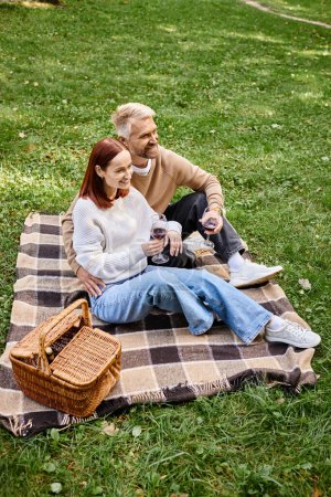Photo for A man and a woman enjoying a peaceful moment on a blanket in the grass. - Royalty Free Image