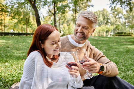 Photo for Couple enjoying wine on grass. - Royalty Free Image
