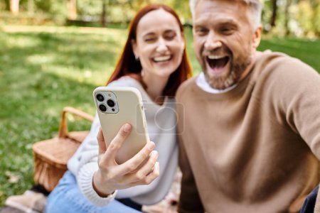 Ein Mann fängt einen freudigen Moment ein, als er ein Selfie mit einer Frau in einem üppigen Park macht.