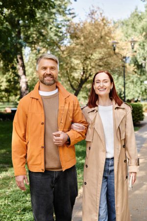 Téléchargez les photos : Couple adulte en tenue décontractée descendre un trottoir de la ville par une journée ensoleillée. - en image libre de droit