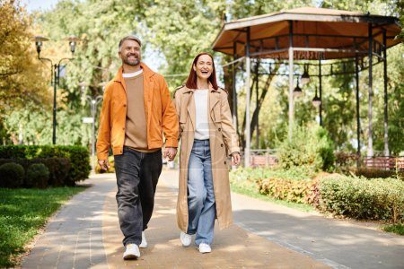 Photo for Casual couple enjoying a leisurely walk in the park. - Royalty Free Image