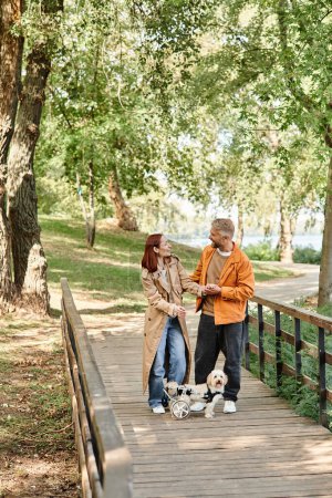 Man and woman with dogs enjoying a stroll on a bridge.