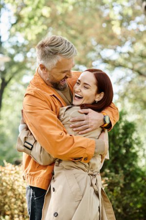 Two adults in casual attire hugging lovingly in a park.