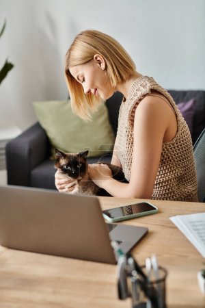 A stylish woman with short hair relaxes at a table with a content cat resting on her lap.