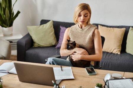 Téléchargez les photos : Une femme aux cheveux courts assise sur un canapé, tenant doucement son chat dans ses bras, profitant d'un moment de compagnie et d'affection. - en image libre de droit