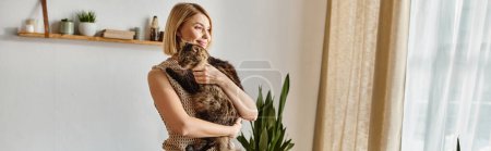 Téléchargez les photos : Une femme se tient gracieusement devant une fenêtre, tenant paisiblement son chat dans une tendre étreinte. - en image libre de droit