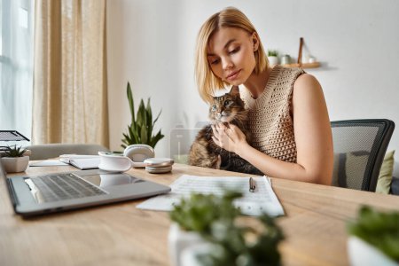 Foto de Una mujer con el pelo corto sentado en un escritorio, sosteniendo pacíficamente a su gato en un ambiente acogedor en casa. - Imagen libre de derechos