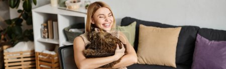 Foto de Una mujer con el pelo corto en una pose relajada en un sofá, sosteniendo un gato contenido en sus brazos. - Imagen libre de derechos