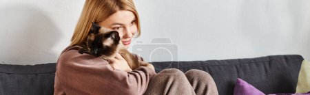 Photo for A woman with short hair serenely cuddles her cat while seated on a couch. - Royalty Free Image