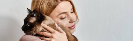 Eine Frau mit kurzen Haaren hält ihre Katze liebevoll dicht vor ihrem Gesicht und fördert ein Band der Zuneigung und Ruhe.