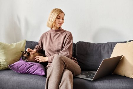 Photo for Woman with short hair sitting on couch, bonding with cat on her lap. Homey atmosphere, relaxed and joyful. - Royalty Free Image