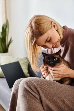 Frau mit kurzen Haaren sitzt auf Couch und hält ihre Katze in einem zarten Moment zu Hause.